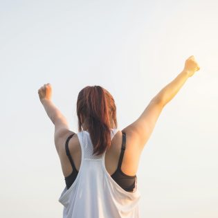 back of woman with arms in the air celebrating.